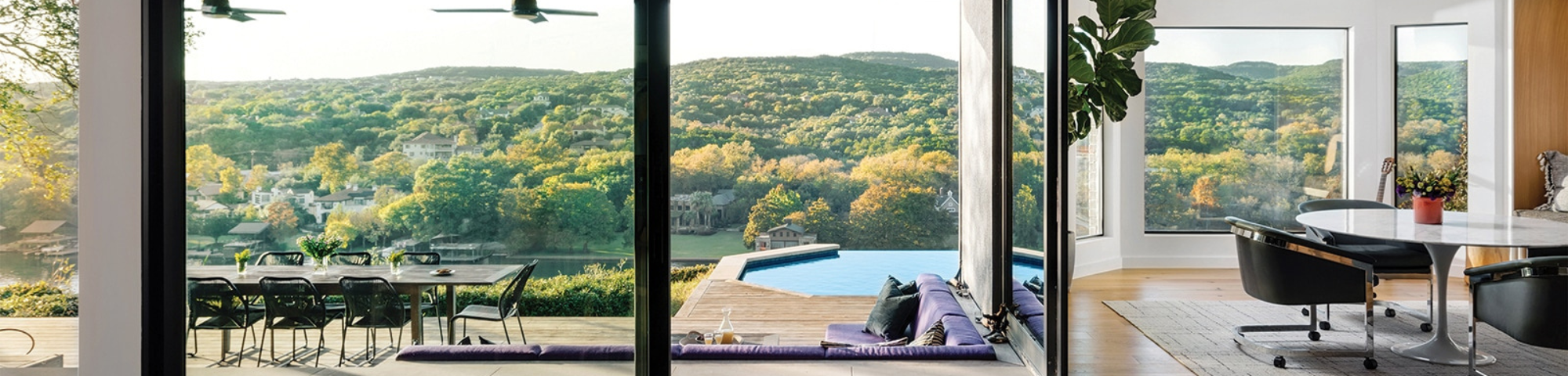 view of countryside from inside resort with large windows and outdoor pool